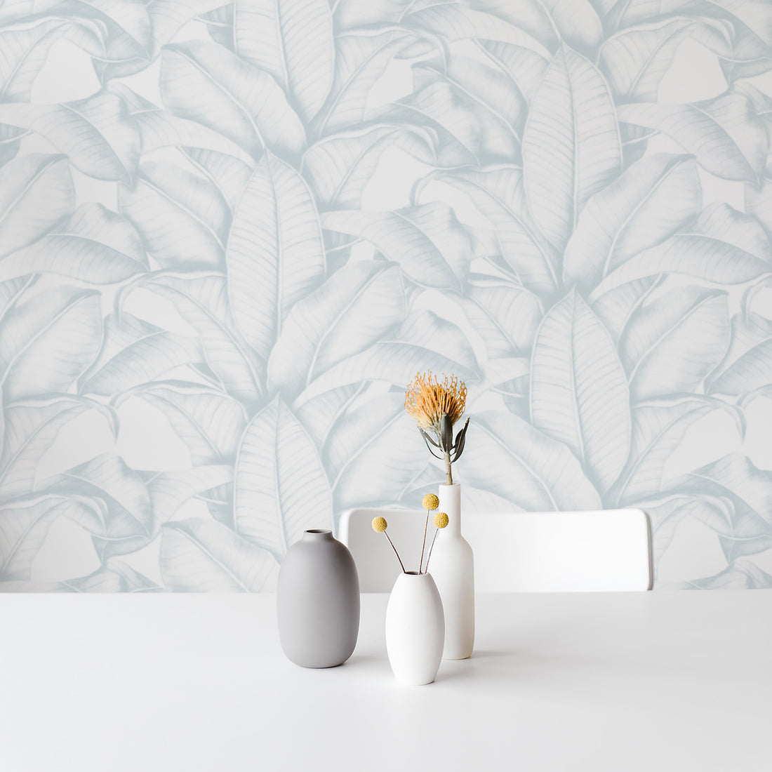 light blue coastal style wallpaper with large tropical leaves