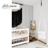 gender neutral bohemian nursery interior with minimal black and white dotted removable wallpaper