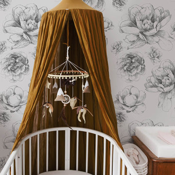 Vintage floral removable wallpaper for bohemian girl's nursery interior with mustard color canopy and baby mobile
