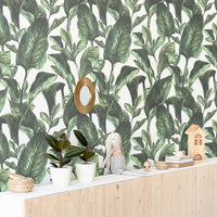 Watercolor botanical leaves removable wallpaper in boho playroom interior with wood cabinets and plush toys